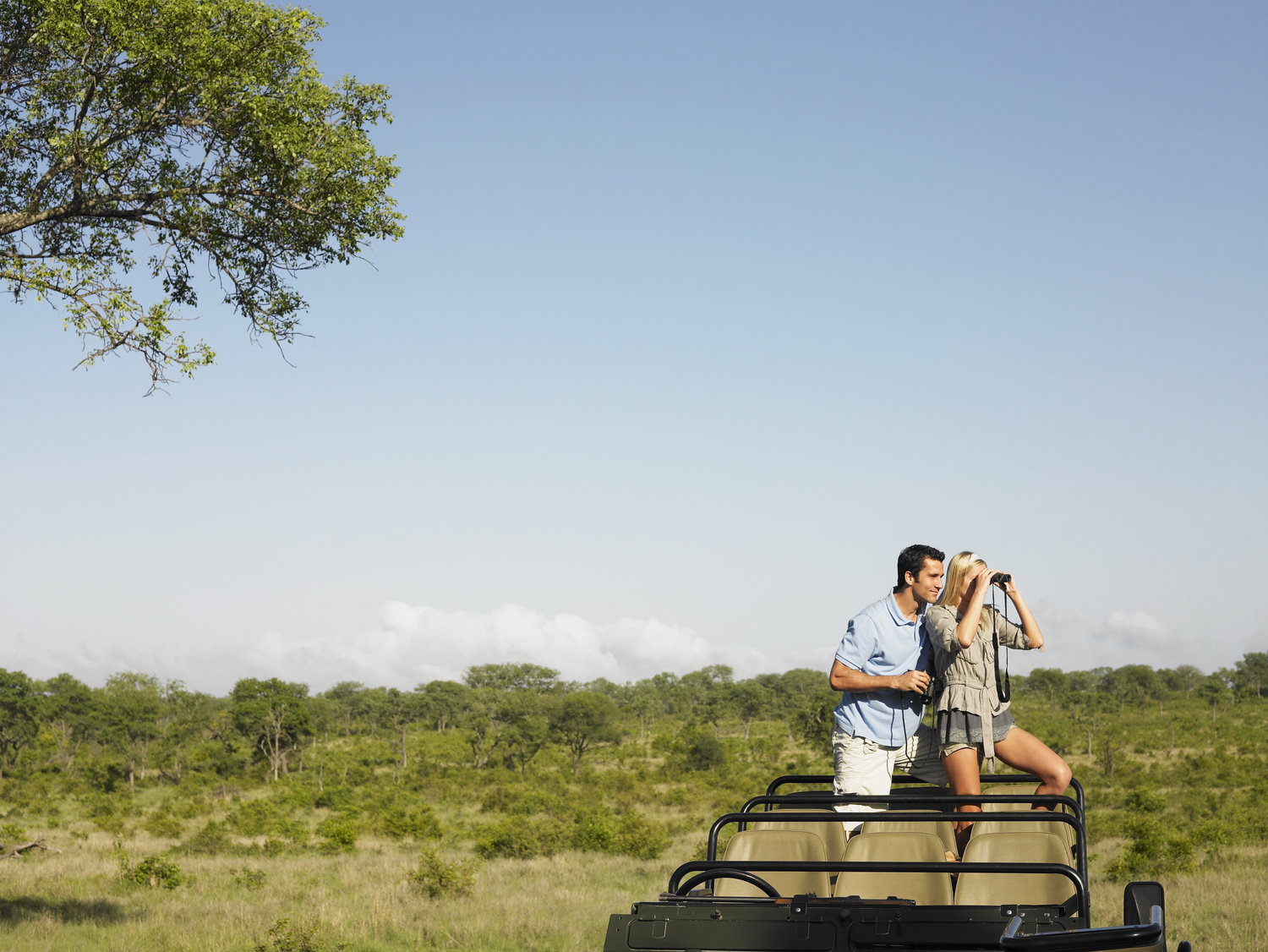 couple dans une Jeep en plein safari dans la savane avec des jumelles